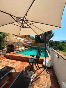an umbrella and a chair next to a swimming pool at Malaka in Coín