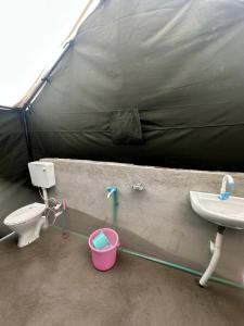 a bathroom with a sink and a toilet and a tent at River Rock Camps in Jispa