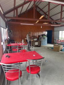 a group of red tables and chairs in a warehouse at River Rock Camps in Jispa