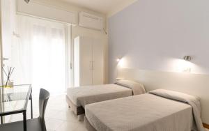 a hotel room with two beds and a glass table at The Sea Hotel in Rimini