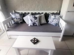 a white couch with pillows and a table in a room at Petite Selfcatering Accommodation Struisbaai SA in Struisbaai