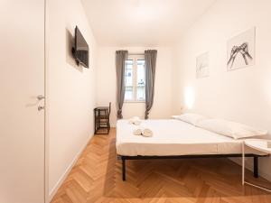 a white bedroom with a bed and a wooden floor at RRRapido Sant' Ambrogio Suites and Rooms - Via Olona in Milan
