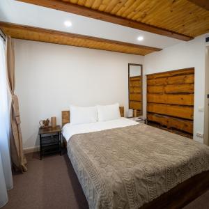 a bedroom with a large bed and a wooden wall at Pensiunea Plaiul Domnesc Runcu in Runcu