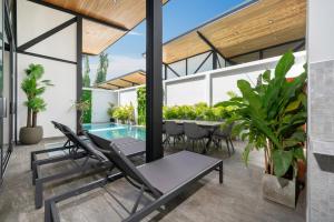 an outdoor patio with a table and chairs and a swimming pool at Sunset Garden 16 - Eco Design Villa with Private Pool near Nai Harn Beach in Rawai Beach
