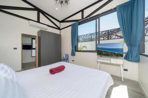 a bedroom with a white bed with a red hat on it at Sunset Garden 16 - Eco Design Villa with Private Pool near Nai Harn Beach in Rawai Beach +37 photos