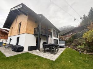 une maison avec un patio avec une table et des chaises dans l'établissement Haus Am Faltenbach - Ferienhäuser Alpenglück, à Oberstdorf