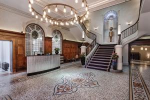 un gran vestíbulo con una escalera y una estatua en Courthouse Hotel Shoreditch en Londres