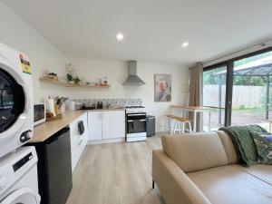 eine Küche und ein Wohnzimmer mit Sofa und Tisch in der Unterkunft Rustic PepperTree Views in Rockingham