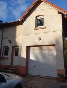 una casa con dos puertas de garaje y un coche en Maisonnette cosy 2 chambres, en Freyming-Merlebach