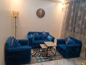 a living room with two blue couches and a clock at Appartement meublé in Meknès +1 photo