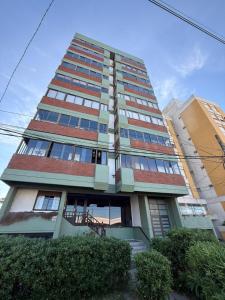 un edificio alto con ventanas y arbustos delante de él en Rincon del Oceano, en Santa Teresita