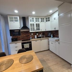 Una cocina con gabinetes blancos y una mesa de madera. en APATRAMET Królowej Jadwigi 12A, en Giżycko 2 fotos más