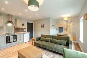Una sala de estar con un sofá verde y una cocina. en Stunning upper villa stay in the City!, en Edimburgo