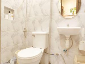 a white bathroom with a toilet and a sink at Amwani Azure in Puerto Princesa City