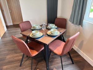 a wooden table with chairs and plates and glasses on it at Sea Marge Seaview Lodges in Overstrand +6 photos