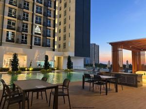 Un patio con mesas y sillas frente a un edificio. en Self Check in Mirai Kajang 3BR, en Kajang