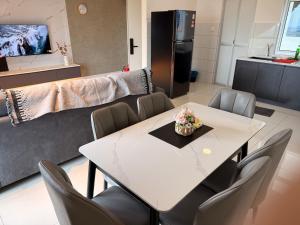 Un comedor con una mesa y sillas blancas. en Self Check in Mirai Kajang 3BR, en Kajang