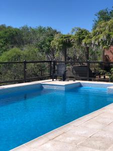 a swimming pool with a chair next to a fence at La Osadia Cabañas y Suites Solo Adultos in Mina Clavero