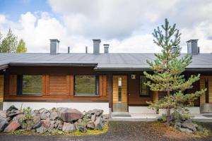 a wooden house with a tree in front of it at Rukariutta Apartments in Ruka