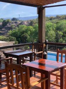 two tables and chairs on a deck with a view of a pool at La Osadia Cabañas y Suites Solo Adultos in Mina Clavero