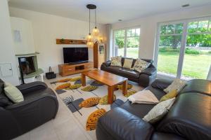 un soggiorno con divani, un tavolo e una TV di Reethaus StrandZeit in Lobbe - Haushälfte 2 a Lobbe