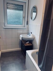 a bathroom with a sink and a tub and a window at Ferienwohnung Rheinglück in Oppenheim