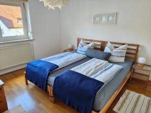 a bedroom with a bed with blue sheets and a window at Ferienwohnung kleines Lautertal in Herrlingen