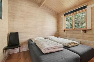 KølkærにあるHyggeligt Sommerhus Nær Herningのベッド2台、椅子、窓が備わる客室です。