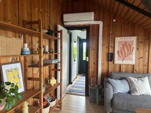 a living room with a couch and wooden walls at Cozy Summer House With New Kitchen And Bathroom in Karrebæksminde