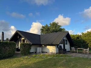 a small white house with a black roof at Cozy Summer House With New Kitchen And Bathroom in Karrebæksminde