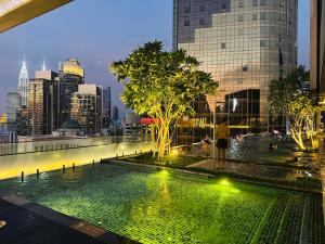 a man standing next to a pool with a city skyline at Axon Residence KL in Kuala Lumpur
