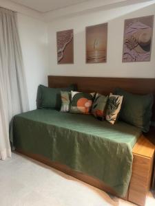 um sofá verde com almofadas num quarto em Tamandaré Mar de Campas Flat 218 Carneiros em Tamandaré mais 20 fotografias