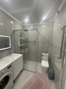 Un baño con ducha, inodoro y lavabo. en ЖК Керуен Сарай, en Türkistan
