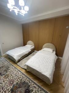 2 camas en un dormitorio con lámpara de araña en ЖК Керуен Сарай, en Türkistan