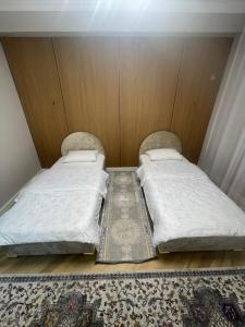 Dos camas individuales en una habitación pequeña con alfombra. en ЖК Керуен Сарай, en Türkistan