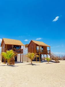 a house on the beach with palm trees in front of it at Chalet Paraiso Canoa 3 na praia - Canoa Quebrada in Aracati +13 photos