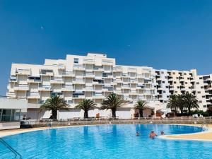 a swimming pool in front of a large building at Les pieds dans l eau au Lydia Playa in Le Barcarès