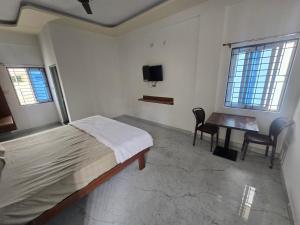 Un dormitorio con cama, escritorio y televisión. en patelru comforts, en Nelamangala