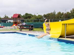 ein kleiner Junge springt von einer Rutsche in einem Pool in der Unterkunft Chalet 87 in Petten