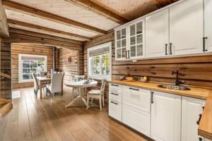 une cuisine avec des placards blancs et une salle à manger avec une table dans l'établissement Luxurious 4 bedroom Mountain Cabin with Gaustatoppen View, à Gaustablikk