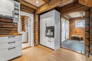 une cuisine avec des armoires blanches et un four à plaques de cuisson dans l'établissement Luxurious 4 bedroom Mountain Cabin with Gaustatoppen View, à Gaustablikk