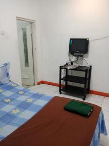 a bedroom with a bed and a tv on a table at Puri Cikole Asri Guest House in Tangkubanperahu