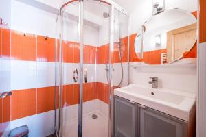 ein orangefarbenes und weißes Badezimmer mit einem Waschbecken und einer Dusche in der Unterkunft Le Grenier - Chalet DDA La Combe in La Combe + 17 Fotos