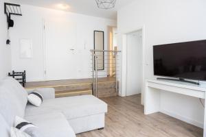 Una sala de estar con un sofá blanco y un televisor de pantalla plana. en Kaisercity Apartment 6, en Núremberg