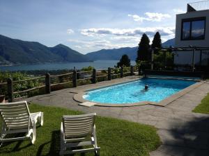 einen Pool mit zwei Stühlen und eine Person im Wasser in der Unterkunft Casa Maria in Locarno