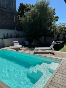 Dormir à Pinarello Villa 9 pers Piscine chauffée 5 min Plage في سانت لوسي دي بورتو فيشيو: حمام سباحة مع كرسيين وطاولة