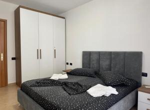a bedroom with a large black bed with white pillows at Holiday Apartmens Neli in Shëngjin