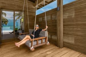 a woman sitting on a swing in a house at Nala Maldives by Jawakara in Lhaviyani Atoll