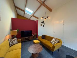 ein Wohnzimmer mit zwei Sofas und einem Fernseher in der Unterkunft Sfeervolle villa met sauna aan de rand van het bos in Putten + 69 Fotos