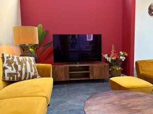 ein Wohnzimmer mit Fernseher, Couch und Tisch in der Unterkunft Sfeervolle villa met sauna aan de rand van het bos in Putten